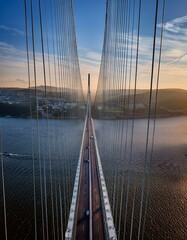 Obraz premium Cars drive across a long cable-stayed bridge at sunset.