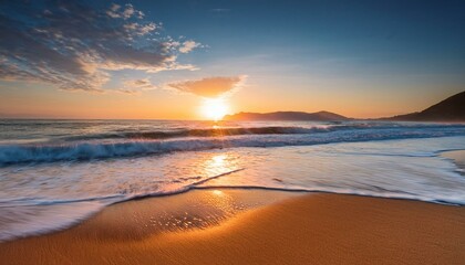Fototapeta premium Golden sunset over tranquil ocean waves lapping a sandy shore.