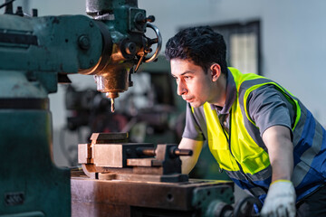A skilled technician works attentively on a heavy duty machine in an industrial workshop. Dressed in safety gear, he demonstrates focus, precision, and craftsmanship in a professional environment.