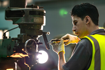A skilled technician works attentively on a heavy duty machine in an industrial workshop. Dressed in safety gear, he demonstrates focus, precision, and craftsmanship in a professional environment.