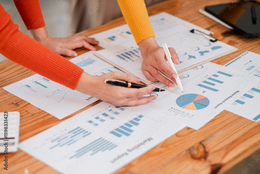 Poster close-up of hands working on financial documents with charts and graphs during a business meeting.