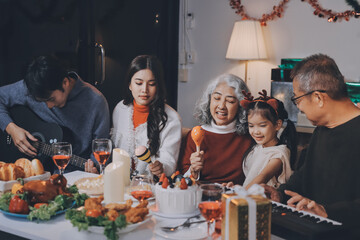 Multi-Generation Family Celebrate Christmas At Home Wearing Santa Hats And Antlers Opening Presents