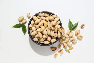 Pistachios in the shell with leaves, on a light background.
