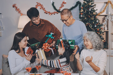 Portrait of Asian family exchanging presents during christmas at home. Attractive happy people holding gift box, celebrate holiday thanksgiving, xmas eve tradition in living room in house together.