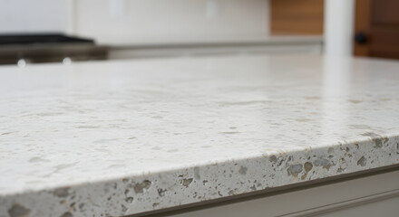 An intimate perspective of a white granite kitchen countertop designed for installation above a kitchen scene that is softly out of focus, showcasing white and wood materials.