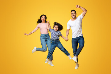 Crazy Offer. Portrait Of Funny Young Arab Family With Little Daughter Jumping Over Yellow...