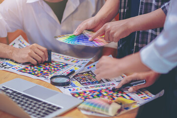 Team graphic designer checking print quality of media graphics proof print and color guides in...