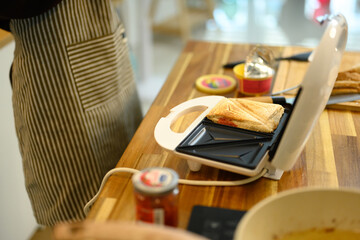 Cropped shot of man in apron making sandwiches in a cozy kitchen