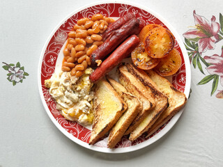 English breakfast - fried egg, baked beans, grilled tomato, beef sausage, and toast. 