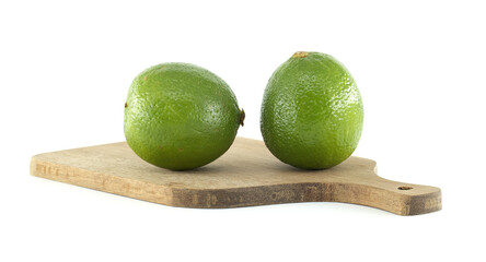 Two fresh limes resting on a wooden cutting board