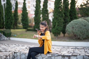 Smiling young Asian woman using smartphone in urban city checking apps mobile outdoors