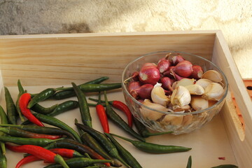 Group of seasoning including hot chili peppers onion, and garlic. laying on the glass of the basket.