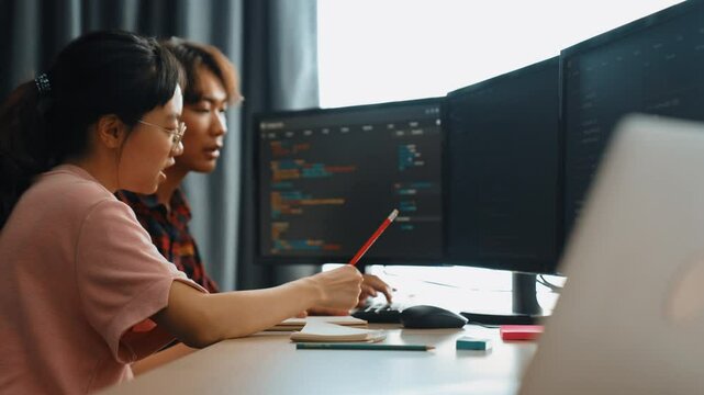 Slow motion back end software developer engineer for computer programming working together on debugging writing computing code, solving complex algorithms display on monitor in office. Burgeoning