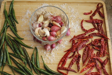 Group of seasoning including hot chili peppers onion, and garlic. laying on the glass of the basket.