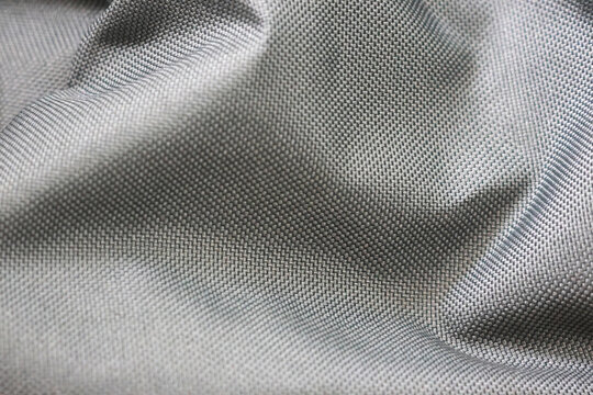 A close-up of a smooth, gray fabric with a tightly woven pattern. The material has a glossy finish and is likely used for outdoor gear such as jackets or backpacks due to its durability