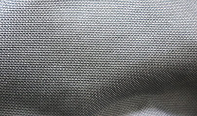 A close-up of a smooth, gray fabric with a tightly woven pattern. The material has a glossy finish...