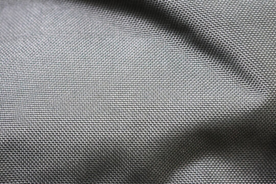 A close-up of a smooth, gray fabric with a tightly woven pattern. The material has a glossy finish and is likely used for outdoor gear such as jackets or backpacks due to its durability