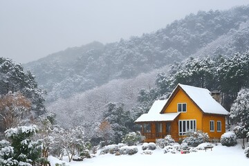 A charming yellow cabin sits amidst a snow-covered mountain forest, offering a peaceful winter escape.