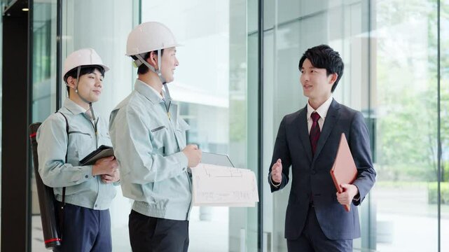 クライアントと打ち合わせをする作業服を着た男性