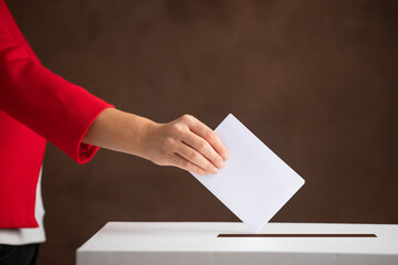 Obraz premium The voter holds his vote ballot paper and places it in the ballot box. Election concept.