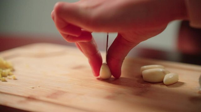 Cutting cloves of garlic by hand with a knife on a cutting board