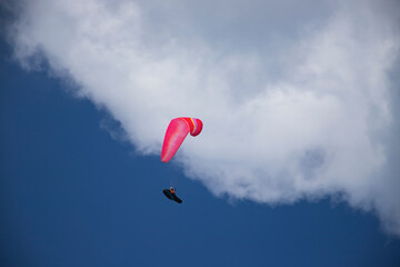 A man with a paraglider in front of a blue sky.
