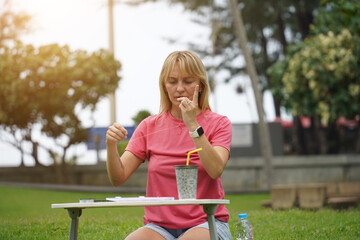 Young woman beading colorful bracelets outdoors in a park