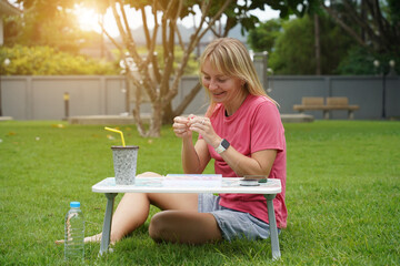 Young woman beading colorful bracelets outdoors in a park
