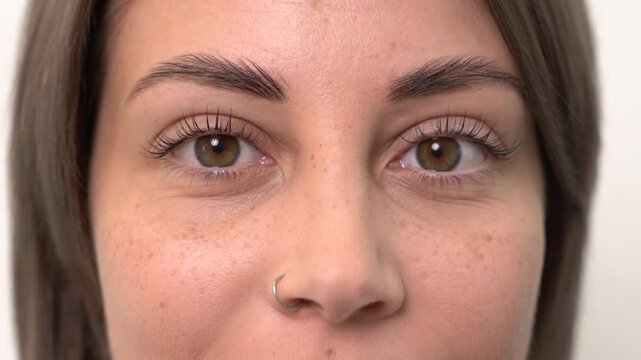 A beautiful young girl opens her eyes after eyelash lamination. Close-up, slow motion