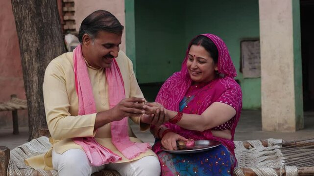 Happy mature indian couple spend time together at home. Husband gift bangles to wife. Rural india.