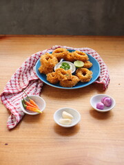 Golden Crispy Onion Rings with Dipping Sauce and Fresh Garnishes