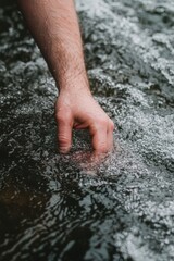 A hand reaching into flowing water, creating ripples and capturing the serene beauty of nature.