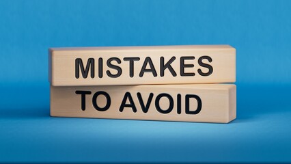 MISTAKES TO AVOID words on wooden blocks. Business and hybrid working culture concept. Wooden cube blocks. Copy space.3D rendering on blue background.