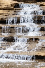 Flowing water cascades over rocky steps, creating a serene and natural landscape scene.