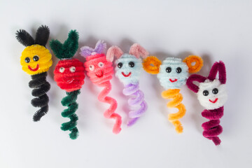 Close-up of a row of cute, colorful finger puppets made from pipe cleaners.