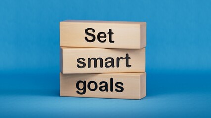Set smart goals written on wooden blocks. Conceptual set smart goals symbol. Wooden cube blocks. Copy space.3D rendering on blue background.