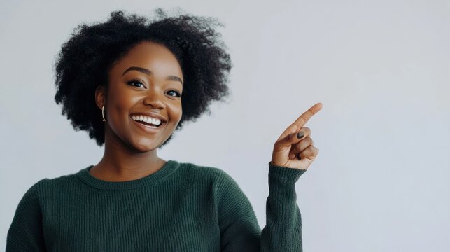 Smiling woman pointing sideways in a casual outfit on solid white background