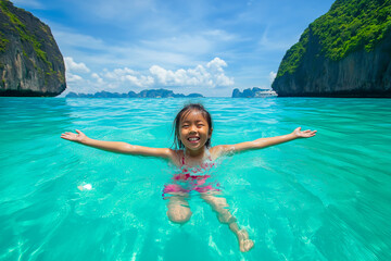 Carefree young girl enjoying a refreshing swim in the crystal-clear waters of maya bay, surrounded...