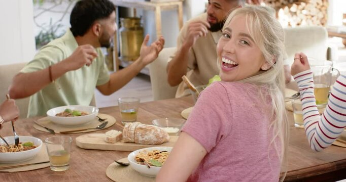 Eating pasta and laughing, young friends enjoying meal together at home