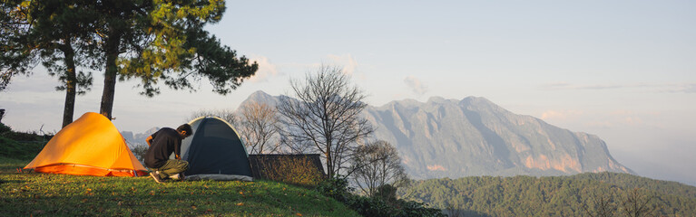 landscape and travel concept with asian man relax see sunset camping tent on mountain