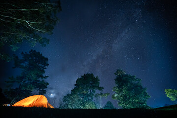 nature traveling with orange camping tent on mountain with milky way background