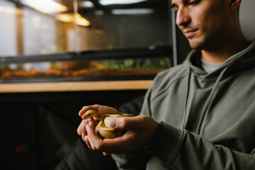 Cheerful pet owner holding an albino ball python near its habitat