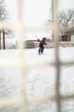 Child Playing Hockey on Outdoor Ice Rink in Winter