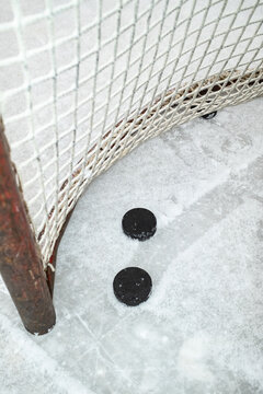 Hockey Pucks Near the Goal on a Snowy Ice Rink