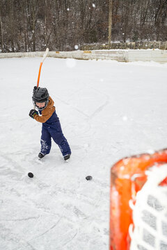 Child Playing Hockey on Outdoor Ice Rink with a Goal in View