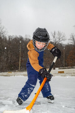 Focused Child Playing Hockey on Snowy Outdoor Rink