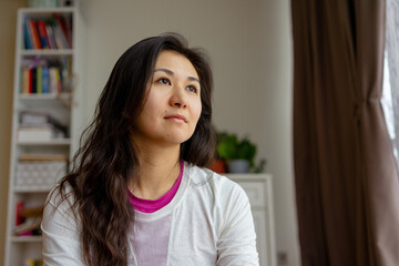 Asian Latin woman thoughtfully looking out the window