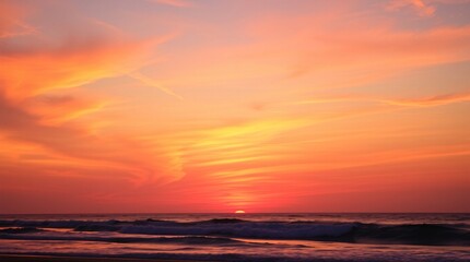 Obraz premium A tranquil shoreline scene showcases a dramatic sunset with vibrant orange, pink, and purple hues illuminating the sky