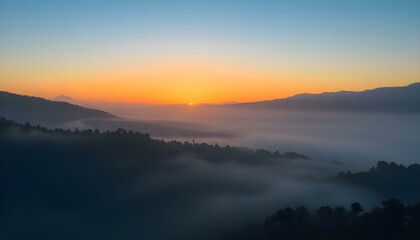 Fototapeta premium the sun is setting over the mountains covered in fog