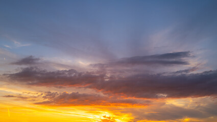 Sunset background. Dramatic majestic scenery sunset. Sky with clouds in sunset sky light background. Sunrise with clouds in various shapes. Calm sunset sky and sun through clouds over.